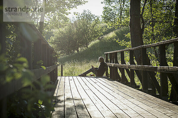 Frau auf Holzbrücke sitzend
