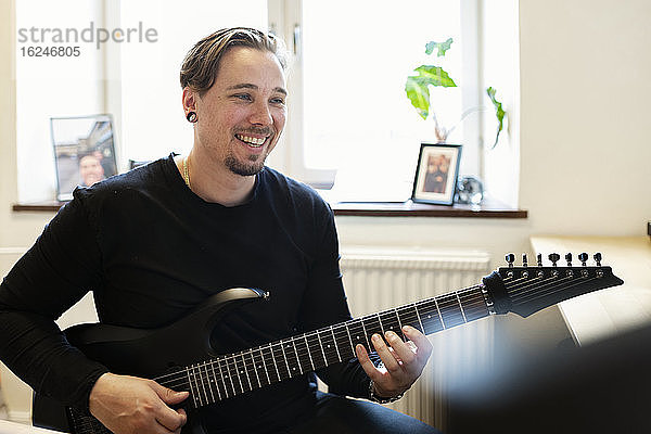 Lächelnder Mann spielt E-Gitarre
