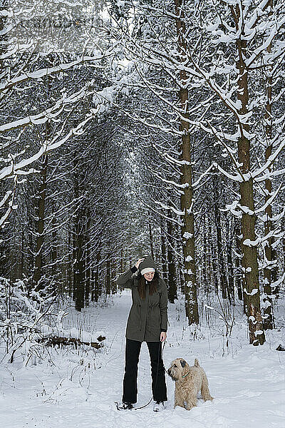 Frau mit Hund im Winterwald