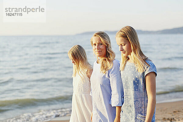 Mutter mit Töchtern spazieren am Strand