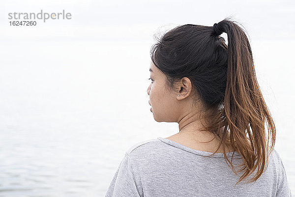 Junge Frau schaut auf das Meer