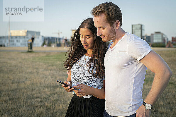 Junges Paar schaut auf ein Mobiltelefon