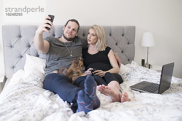 Paar auf dem Bett nimmt Selfie