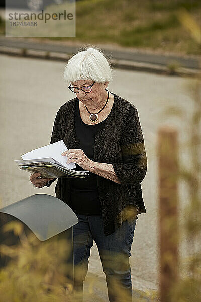 Ältere Frau steht in der Nähe des Briefkastens