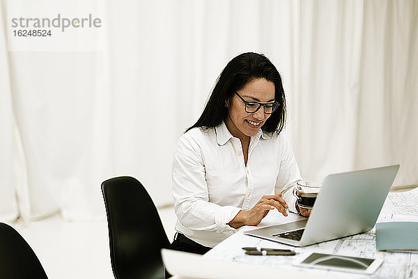 Lächelnde Geschäftsfrau mit Laptop bei der Arbeit