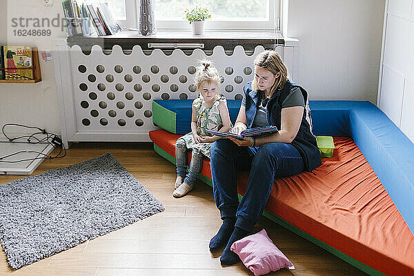 Lehrerin liest einem Mädchen im Kindergarten vor