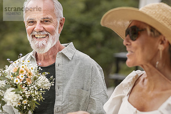 Älterer Mann hält Blumenstrauß