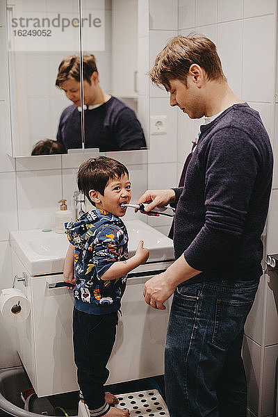 Vater hilft seinem Sohn beim Zähneputzen
