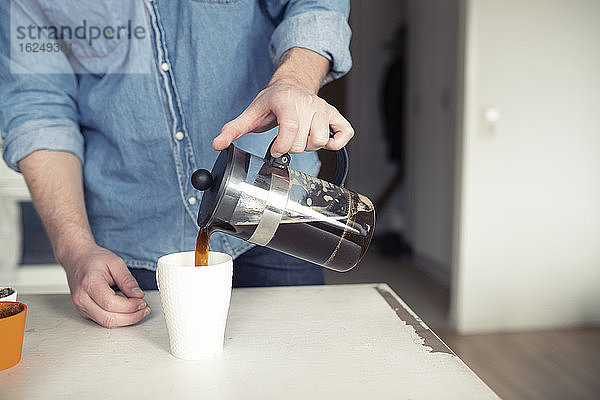 Mann gießt Kaffee aus französischer Presse