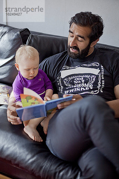 Vater liest seinem kleinen Mädchen ein Buch vor