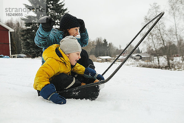 Mutter mit Sohn auf Schlitten Schneeschaufel