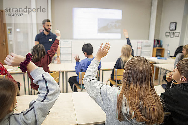 Kinder heben die Hände im Klassenzimmer