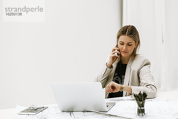 Geschäftsfrau am Schreibtisch  die über ein Mobiltelefon spricht