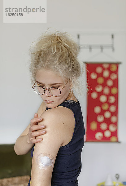 Junge Frau überprüft Insulinpumpe auf ihrer Schulter