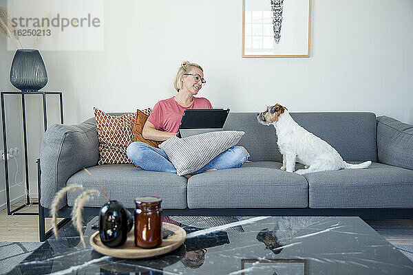 Frau auf Sofa sitzend mit Hund