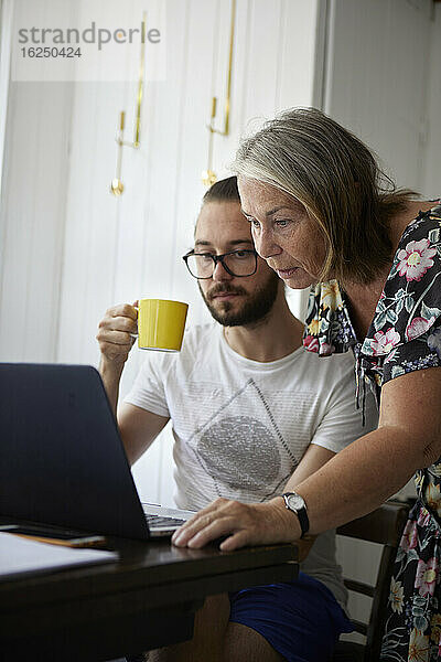 Ältere Frau benutzt Laptop mit erwachsenem Sohn