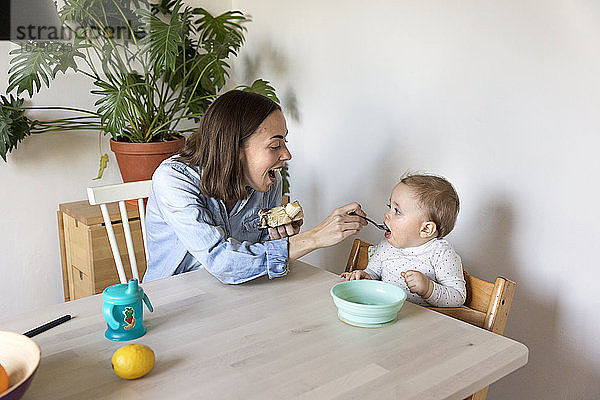 Mutter füttert Baby am Tisch