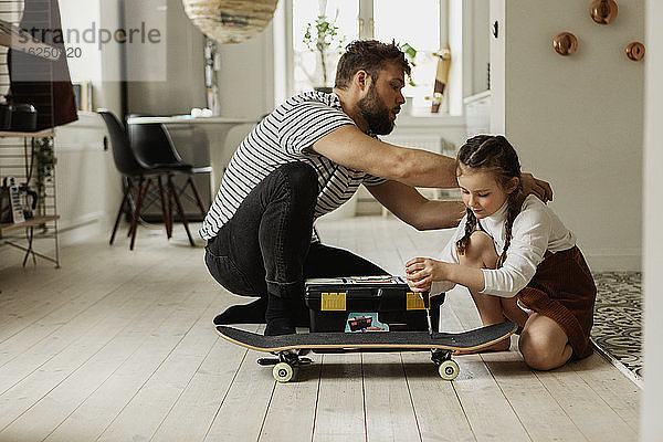 Vater mit Tochter repariert Skateboard