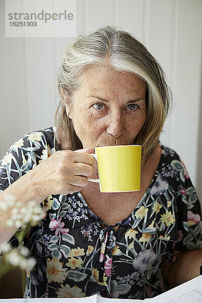 Ältere Frau trinkt aus einem Becher