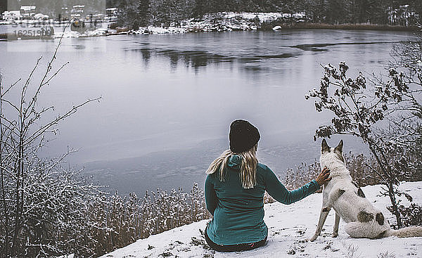 Frau mit Hund am See sitzend