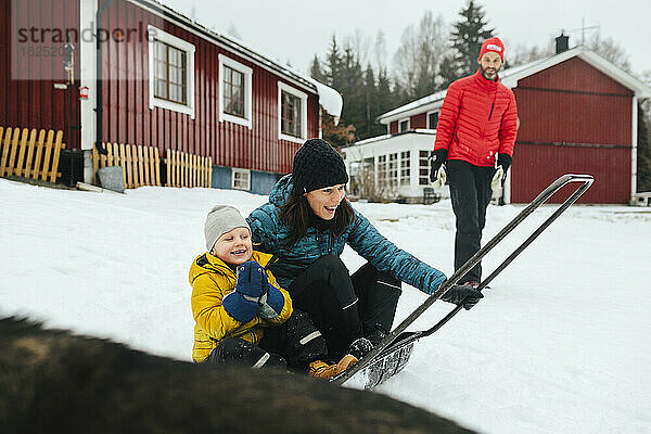 Mutter mit Sohn auf Schlitten Schneeschaufel