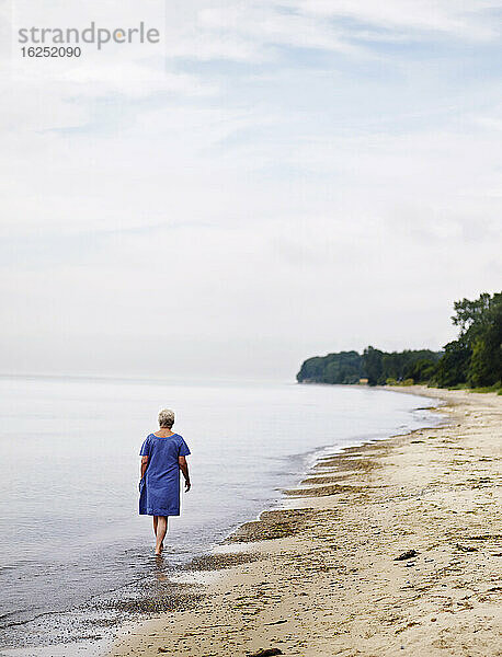 Ältere Frau geht am Strand spazieren