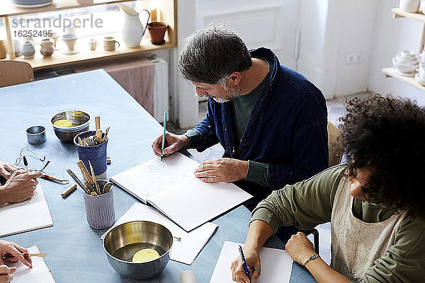 Hochwinkelansicht Mann und Frau beim Zeichnen am Tisch während des Kunstunterrichts