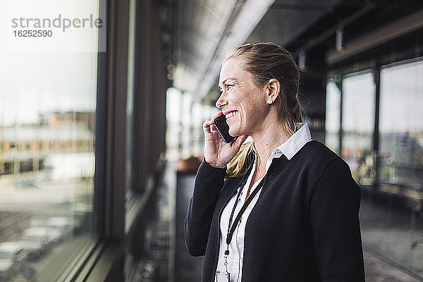 Lächelnder Unternehmer beim Telefonieren am Arbeitsplatz im Stehen