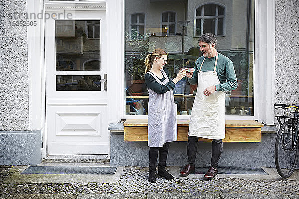 Lächelnde männliche und weibliche Kollegen beim Kaffeetrinken vor dem Kunstatelier