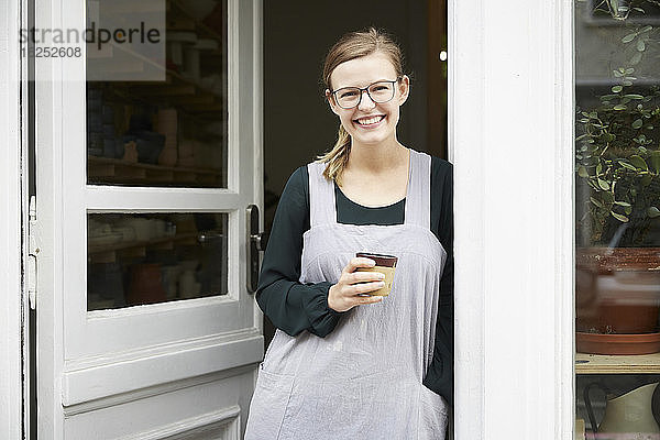 Porträt einer selbstbewussten Besitzerin beim Kaffee trinken am Eingang des Kunstateliers