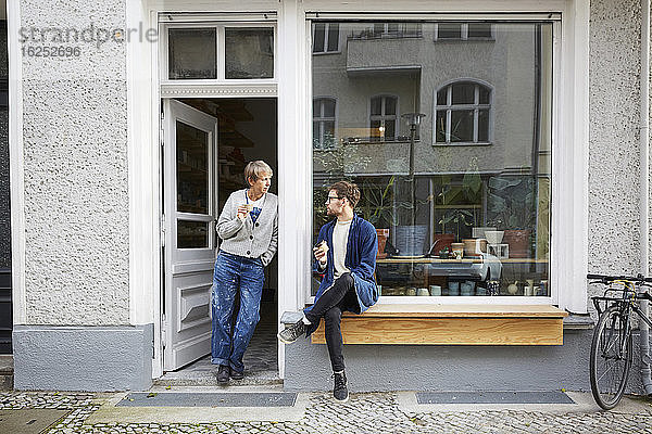 Männliche und weibliche Kollegen beim Kaffee trinken am Eingang des Kunstateliers