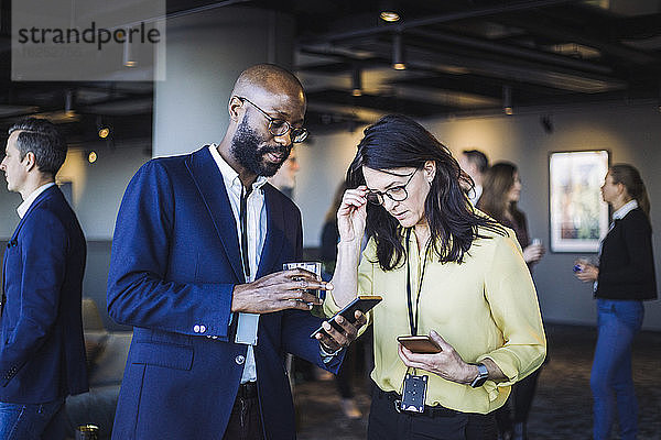Unternehmer zeigt einer Kollegin im Büro ein Smartphone