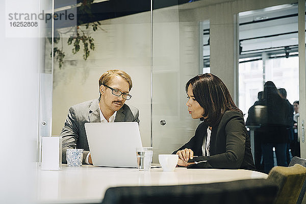 Männliche und weibliche Kollegen diskutieren während sie im Büro sitzen