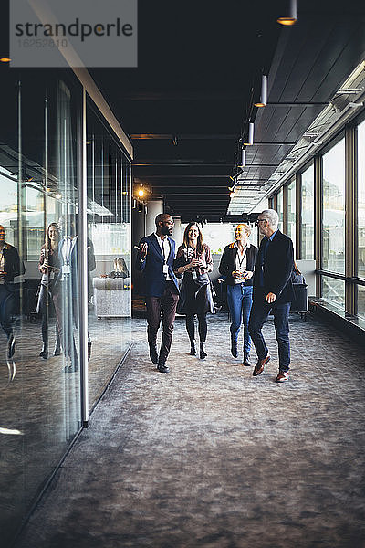 Unternehmer und Unternehmerinnen gehen im Bürokorridor