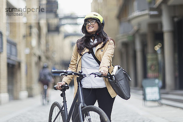 Porträt einer lächelnden Frau mit Helm und Fahrrad auf der Strasse