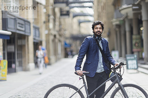 Porträt eines selbstbewussten Geschäftsmannes mit Fahrrad in der Stadt