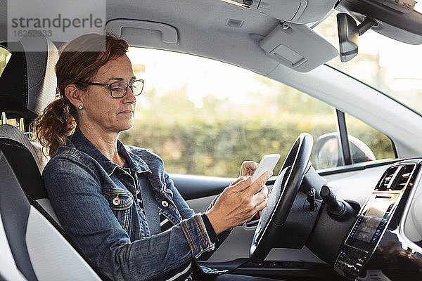 Reife Frau schreibt SMS  während sie im Auto sitzt