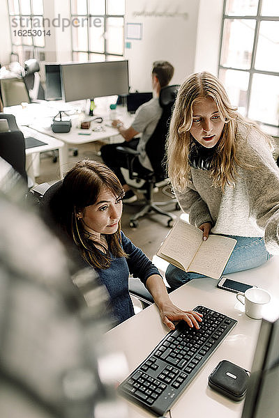 Berufstätige Frauen diskutieren bei der Arbeit am Computer am Arbeitsplatz