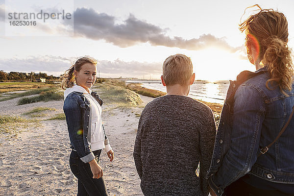 Porträt eines Teenagers mit Familie am Strand
