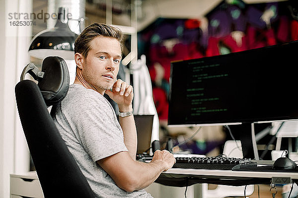 Porträt eines im Büro sitzenden männlichen Computerprogrammierers