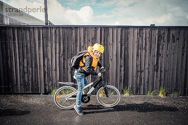 Porträt eines lächelnden Jungen über einem Fahrrad auf der Straße