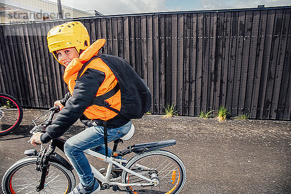 Porträt eines lächelnden Jungen beim Fahrradfahren auf der Straße