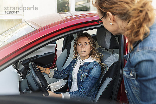 Tochter sieht Mutter an  während sie in den Ferien Autofahren lernt