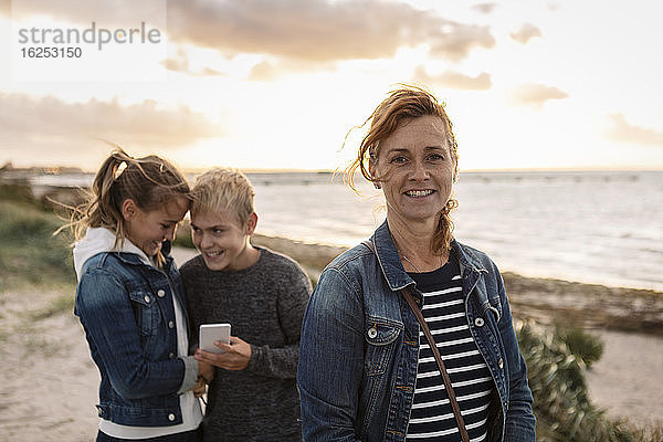 Porträt einer lächelnden Mutter mit Kindern am Strand