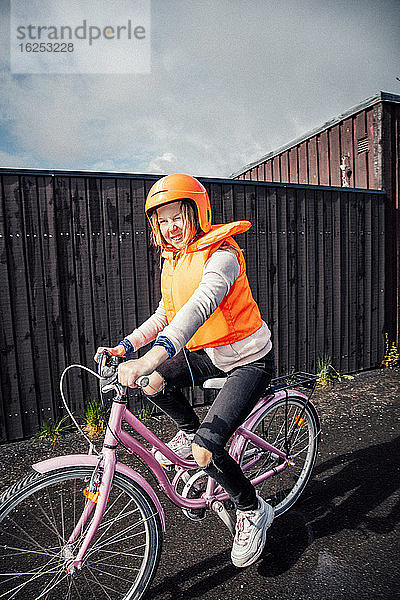 Lächelndes Mädchen fährt Fahrrad auf der Straße