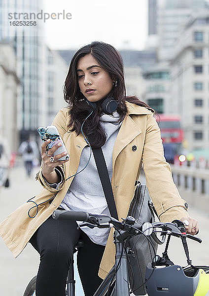 Frau auf Fahrrad mit Smartphone in der Stadt