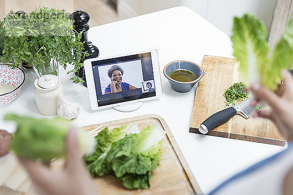 Frau beim Salatkochen und Video-Chat mit Freunden in der Küche