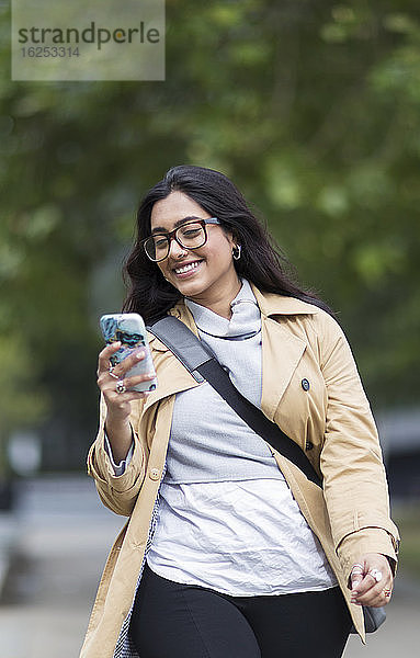 Lächelnde Frau geht mit Smartphone