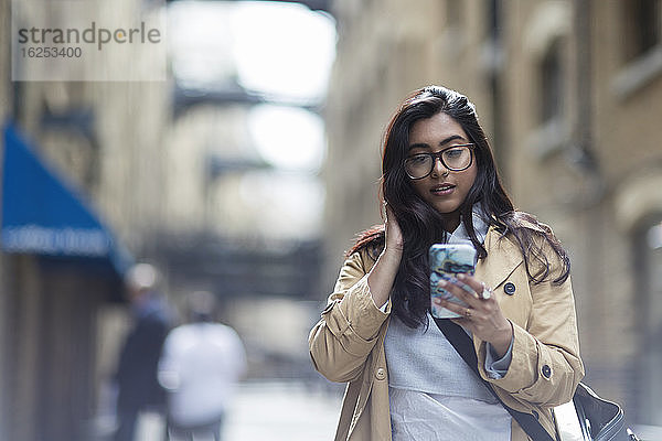 Geschäftsfrau benutzt Smartphone auf dem Bürgersteig