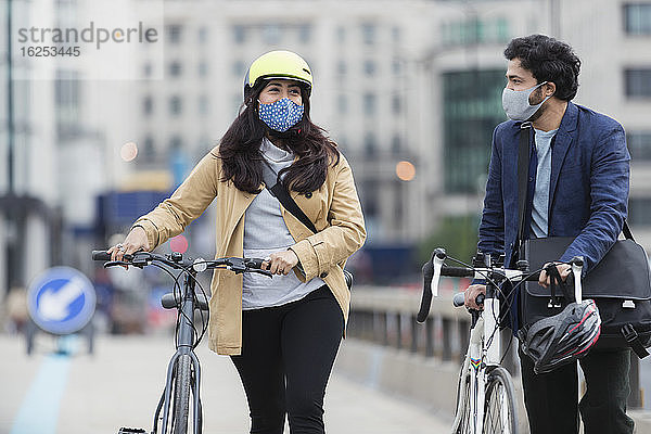 Geschäftsleute mit Gesichtsmasken beim Radfahren auf der Stadtbrücke